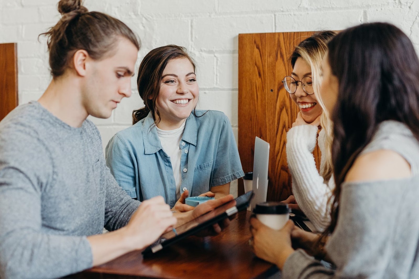 Un groupe diversifié de personnes collaborant et souriant autour d'une table, représentant la communauté AimaHelp.
